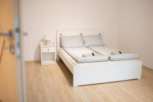 a white bed in a white room with a night stand at Domek na Lipowej in Stare Miasto