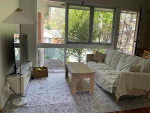 Una sala de estar con un sofá blanco y una mesa. en Marsfield-Queen-MacUni-MacCentre-Bus-Woolworth, en Sídney