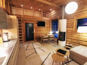 a living room with wooden walls and a kitchen with a stove at Syöte Cottage in Syöte