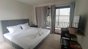 a bedroom with a large white bed and a balcony at ธัญญ์ รีสอร์ท หินดาด in Ban Pak Nam Chumphon +3 photos