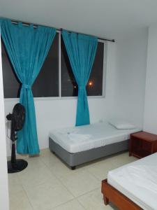 a bedroom with a bed and a window with blue curtains at Hotel Camino al Llano in Villavicencio