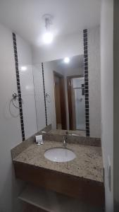 Un baño con lavabo y un espejo grande. en Boulevard suite hotel suite 434, en Caldas Novas