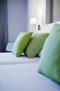 Una cama con almohadas verdes encima. en Mir Octavio en Algeciras