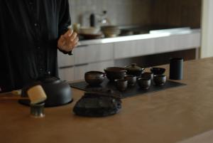 a man standing in a kitchen with cups on a counter at 雲居月-kumoizuki- in Ginowan