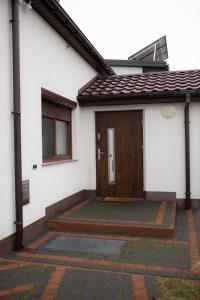 a house with a wooden door and a patio at Domek na Lipowej in Stare Miasto