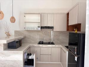 a kitchen with white cabinets and a black refrigerator at D'rei guesthouse in Canggu