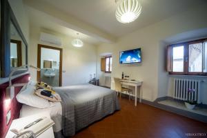 a bedroom with a bed and a desk and a television at Chiostro Delle Monache Hostel Volterra in Volterra
