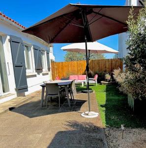 een patio met een tafel en een parasol bij Ile de Noirmoutier - Maison NO'VA refaite à neuf in LʼÉpine