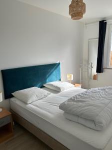 een slaapkamer met een groot wit bed met een blauw hoofdeinde bij Ile de Noirmoutier - Maison NO'VA refaite à neuf in LʼÉpine