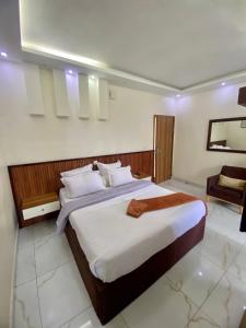 a bedroom with a large bed and a chair at Chambre meublée - Bonapriso in Douala