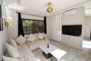 Una sala de estar con un sofá y un televisor. en Villa Blanca - Pureté & Modernité, en Essaouira