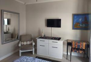 Una habitación con un televisor, una silla y un espejo. en A Lighthousee delight, en Swakopmund 6 fotos más