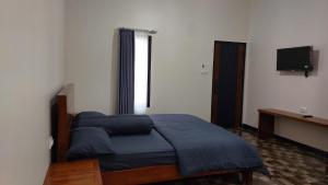 a bedroom with a bed and a desk and a television at See Sea Hostel & Resto in Jepara +2 photos