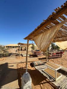 a wooden shelter with a bench and an umbrella at Le xury camp in Hassilabied