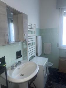 a white bathroom with a sink and a toilet at Tamika's House in Udine