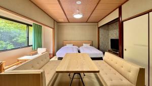 a room with a bed and a table and a tv at Ureshino Onsen Yusyuku Sarayama in Ureshino