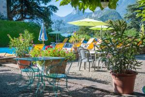 een patio met stoelen en tafels met planten en parasols bij Hotel du Lac in Talloires