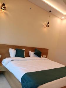 a bedroom with a large bed with two lights at Aamaya Inn in Haldwāni