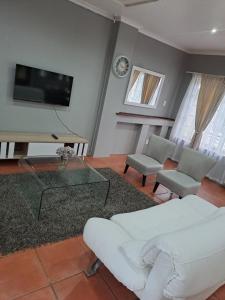 Una sala de estar con un sofá blanco y un televisor. en Sabs Place, en Gillitts
