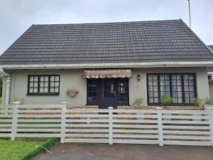 una pequeña casa con una cerca blanca delante de ella en Sabs Place, en Gillitts