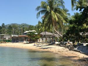 a beach with palm trees and a building at Smiley Bungalows Guesthouse in Srithanu