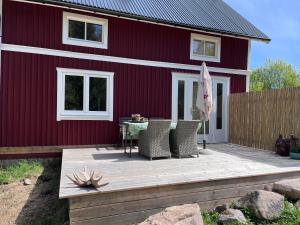 a red barn with a table and chairs on a deck at Huisje weltevreden in Ekshärad