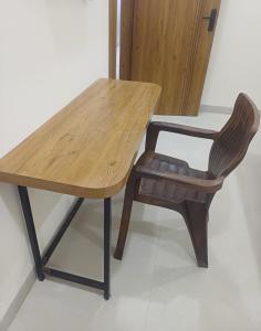 a wooden table and a chair sitting at a table at Hotel Soni Indore in Indore