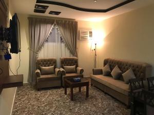 a living room with two couches and a table at المهيدب 2 للشقق المخدومة - اقتصادى in Buraydah