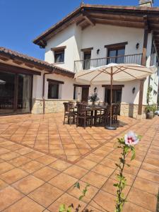 een patio met een tafel en een parasol bij Casa Eloy in Argüero