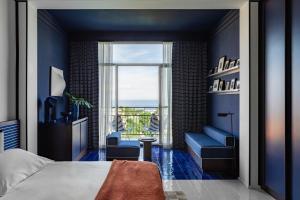 a bedroom with blue walls and a bed and a window at Grand Hotel Flora in Sorrento