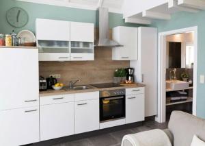 een keuken met witte kasten, een wastafel en een fornuis bij Ferienhaus Clara in Wardenburg