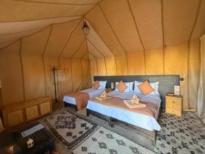 a bedroom with two beds in a tent at Camel luxury camps Merzouga in Merdani