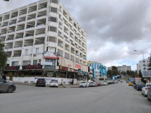 a large white building on a city street with parked cars at Campus and Clinique Appart in Tunis