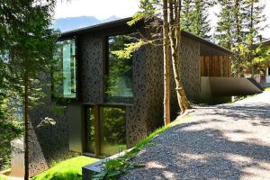 ein Haus mit Glasfenstern an der Seite in der Unterkunft Caselva Arosa Mountain Residence by Arosa Stay in Arosa