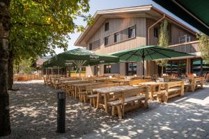 a row of wooden tables and umbrellas in front of a building at Gasthof zur Post in Bad Wiessee
