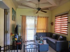 a living room with a couch and a ceiling fan at Regina's Vacation House in Tayud