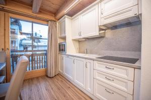 een keuken met witte kasten en een balkon bij Chalet Abete in Livigno