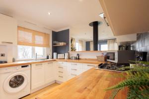 a kitchen with white cabinets and a washing machine at Secluded Sanctuary On The River in Christchurch