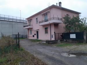 une maison rose avec une clôture devant elle dans l'établissement 2 passi dalla fiera SOGNI D'ORO, à Vérone
