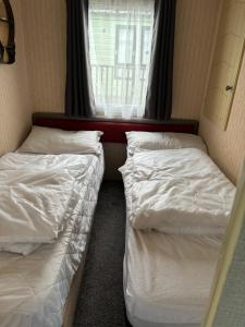 twee bedden in een kleine kamer met een raam bij Bobbys Bolthole2 in Heysham