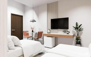 a living room with white furniture and a tv at Suchanan Serviced Apartment โรงแรมสุชานันท์ in Ban Chang