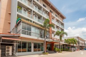 an apartment building with palm trees in front of it at Suchanan Serviced Apartment โรงแรมสุชานันท์ in Ban Chang