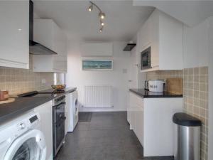 Cozy Guest Room in Family Home, Close to Aldershot Town Centre في ألدرشوت: مطبخ مع خزائن بيضاء وغسالة ومجفف +3 صور