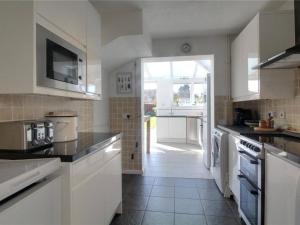 Cozy Guest Room in Family Home, Close to Aldershot Town Centre في ألدرشوت: مطبخ به أجهزة بيضاء ونافذة كبيرة