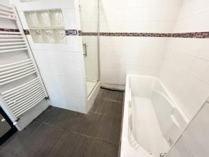 Un baño blanco con bañera y ducha. en Charmante Maison partagée à 5 min d'Orly et 15 min de Paris, en Athis-Mons