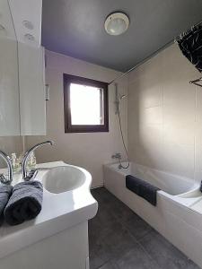 Appartement Le Bargy في Scionzier: حمام مع حوض استحمام ومغسلة وحوض استحمام