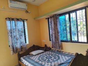 ein Schlafzimmer mit einem Bett in einem Zimmer mit Fenstern in der Unterkunft Farm House Shetgeri in Ankola