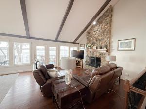 een woonkamer met lederen meubels en een stenen open haard bij Edgewater-Lakefront 3 BD25BADeckDockGril-16P in Laguna Beach