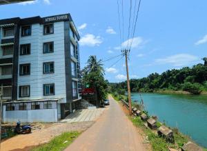 a building on the side of a road next to a river at Atholi Residency in Mukkam
