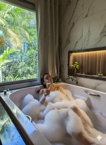 a woman sitting in a bath tub with a glass of wine at Recanto do Príncipe, privacidade, paz e contato Com a natureza in Marechal Floriano